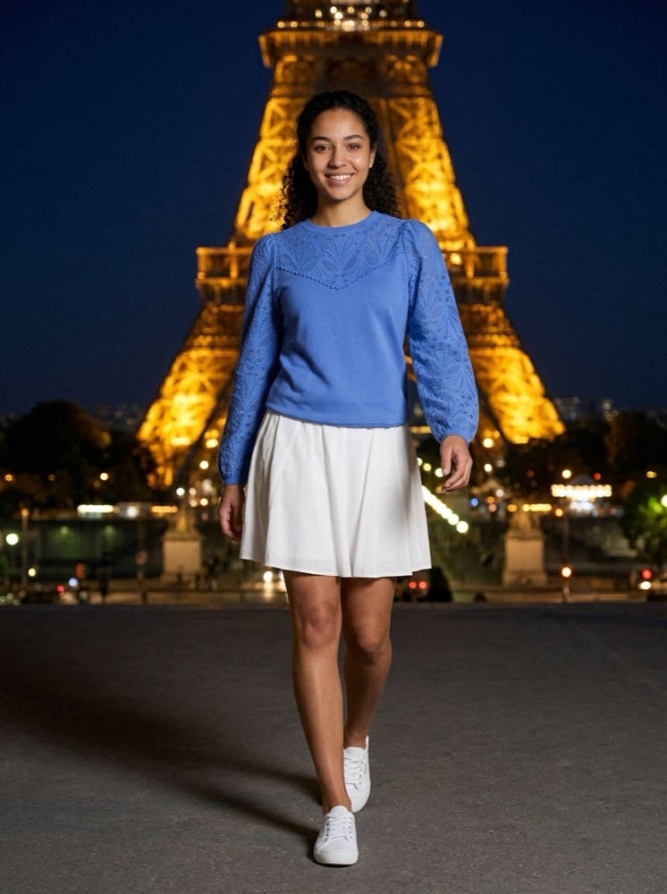 The same model and sweatshirt in front of the Eiffel Tower at night